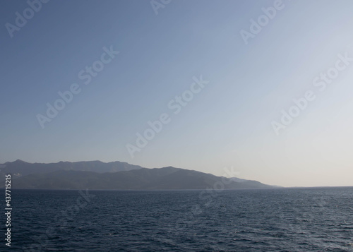 Distant land in the ocean, tranquil calm water, beautiful blue ocean and blue sky, travel destination, summertime season, vacation in the nature
