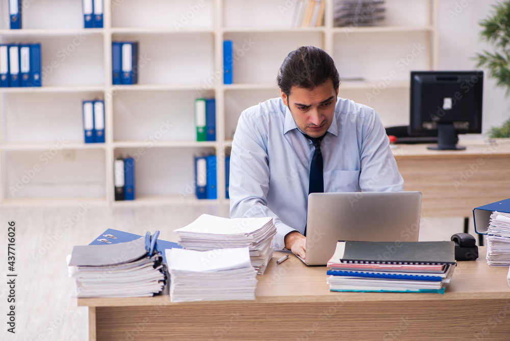Young male employee and too much work in the office Young male employee and too much work in the office