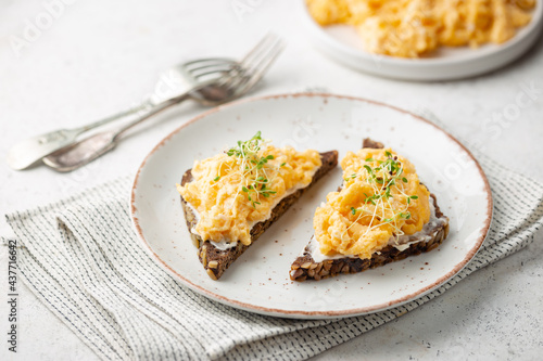 Fotografie Scrambled egg sandwich with cream cheese on rye toast for breakfast on white background