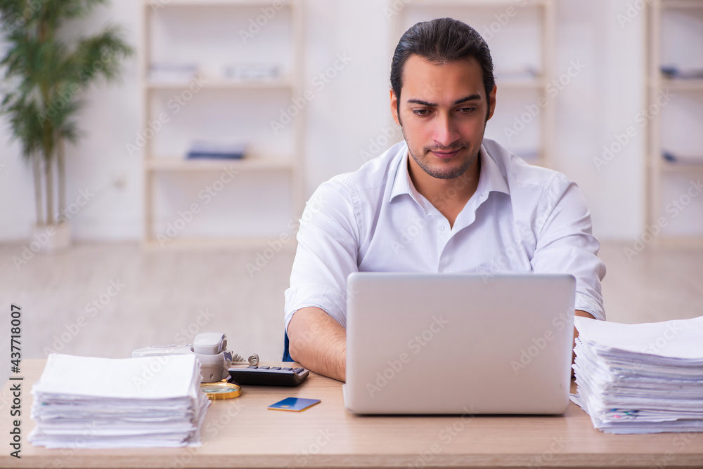 Young businessman employee unhappy with excessive work in the office Young businessman employee unhappy with excessive work in the office