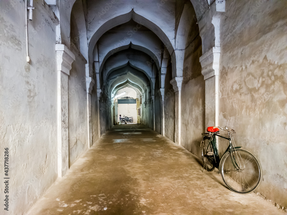A bicycle parked in a long arcaded corridor inside the ancient Maratha Palace in Thanjavur.