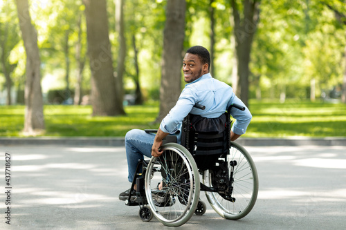 Joyful handicapped black man in wheelchair spending time at city park, full length © Prostock-studio