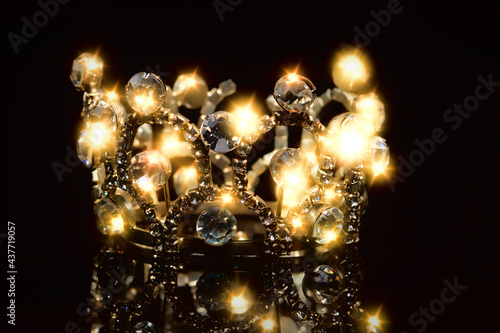 Gold crown with shiny stones on a black background. © Светлана Лазаренко