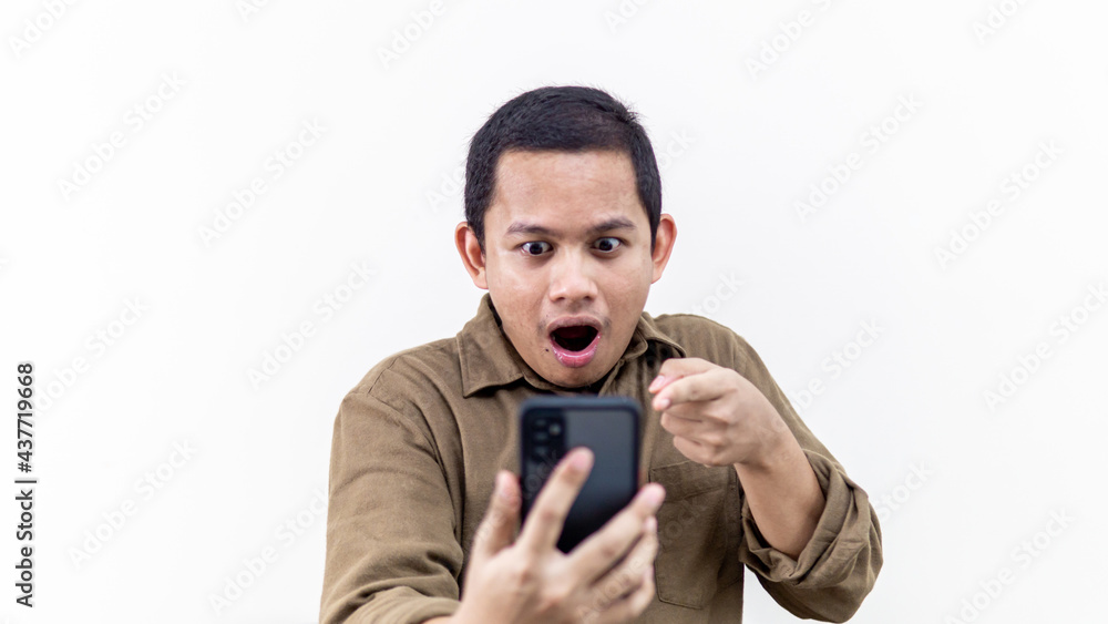 Wow and shocked face expression of young Asian Malay man looking at the smartphone. Wow and shocked face expression of young Asian Malay man looking at the smartphone.