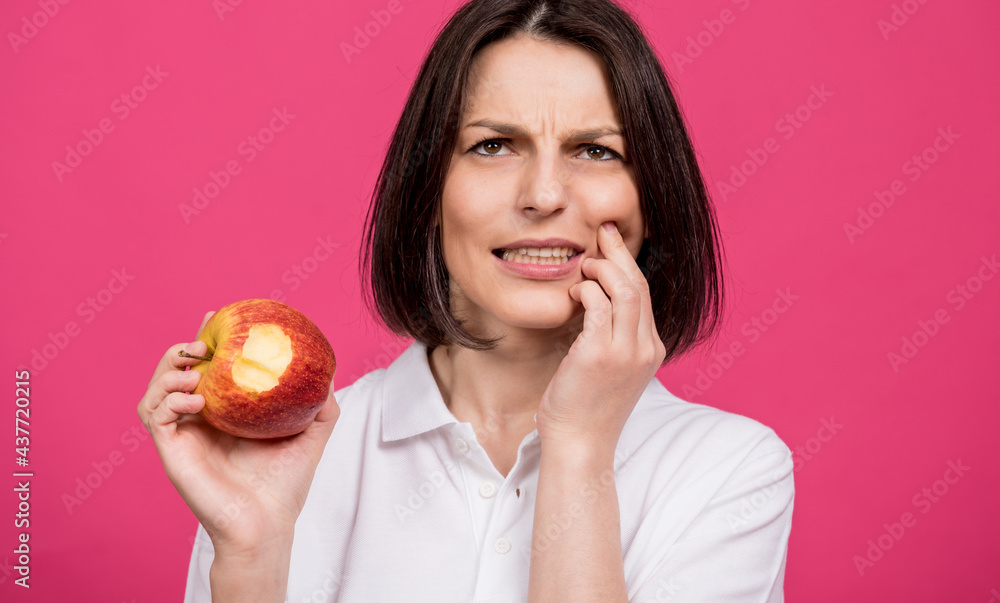 Beautiful young woman bites a big apple and has a toothache Beautiful young woman bites a big apple and has a toothache
