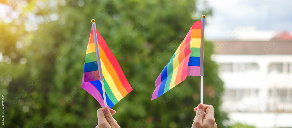 hands showing LGBTQ Rainbow flag on green nature background. Support Lesbian, Gay, Bisexual, Transgender and Queer community and Pride month concept hands showing LGBTQ Rainbow flag on green nature background. Support Lesbian, Gay, Bisexual, Transgender and Queer community and Pride month concept