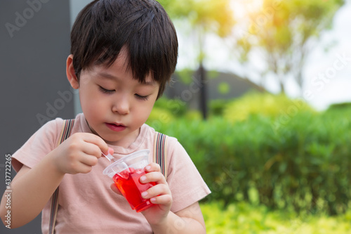 Cute little child love eating sweets or snack. Handsome little boy enjoy eating gelatin or jelly. Adorable kid like eating snack. He feel happy when he eat favorite sweet with garden background photo
