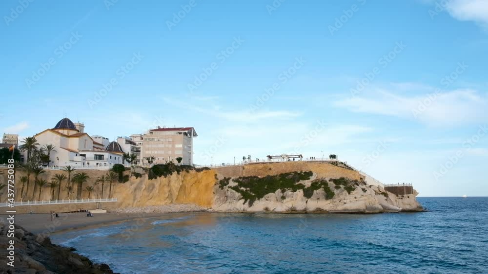 Benidorm old town with Church of Sant Jaume, Mirador and Mediterranean balcony on cliff. Waves crashing against sandy beach. Birds flying and spanish flag waving. Costa Blanca region, Spain Benidorm old town with Church of Sant Jaume, Mirador and Mediterranean balcony on cliff. Waves crashing against sandy beach. Birds flying and spanish flag waving. Costa Blanca region, Spain