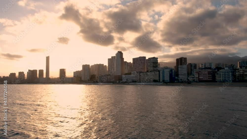 Sunset over Benidorm and Poniente beach, Spain. Skyline with skyscrapers, city buildings and calm sea waves and sunlight on water. Beautiful Costa Blanca region Sunset over Benidorm and Poniente beach, Spain. Skyline with skyscrapers, city buildings and calm sea waves and sunlight on water. Beautiful Costa Blanca region