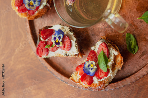 Strawberry toast brioche with cream cheese decorated with flowers and basil fflat lay close up photo