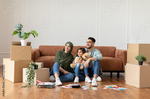 Happy man, woman and girl looking up at home © Prostock-studio