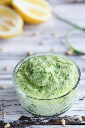 Garlic Scape Pesto with fresh homegrown ingredients of lemons and pine nuts over a white rustic wood table. Selective focus with blurred foreground and background.