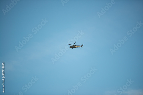 The helicopter flies in the blue sky on a summer day