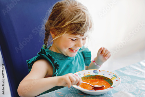 Obraz na plátně Little preschool girl eating healthy vegetable tomato soup for lunch