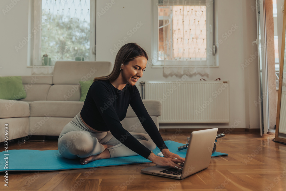 Woman using laptop and airpods while training at home Stock Photo | Adobe  Stock