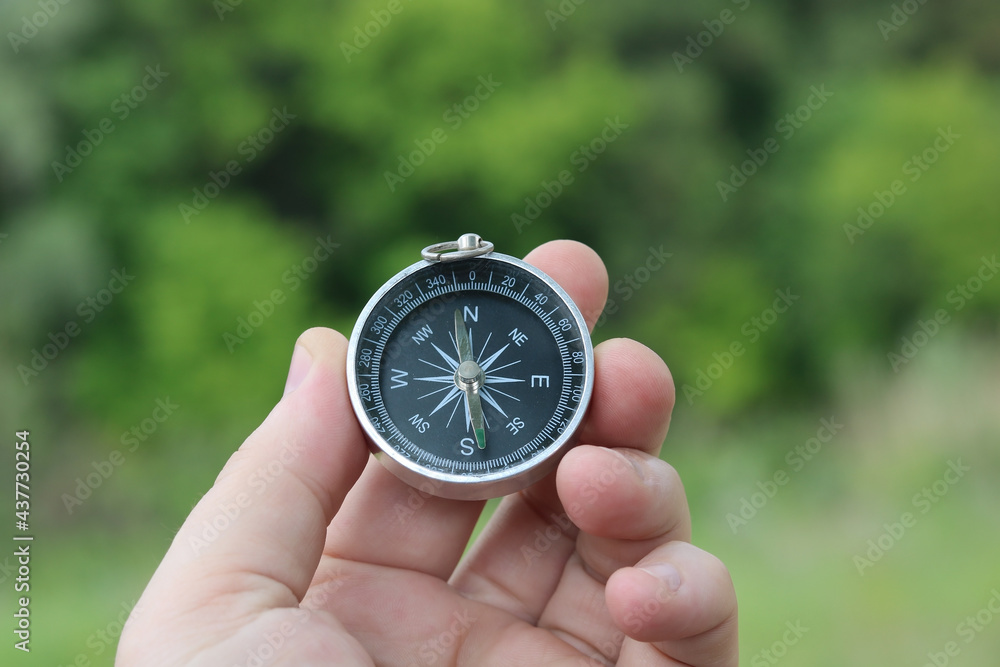 Old classic navigation compass in hand on natural background as symbol of tourism with compass, travel with compass and outdoor activities with compass Old classic navigation compass in hand on natural background as symbol of tourism with compass, travel with compass and outdoor activities with compass