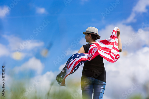 Woman holding the american flag outdoors on a meadow.  4th of July - Independence day. © belyaaa