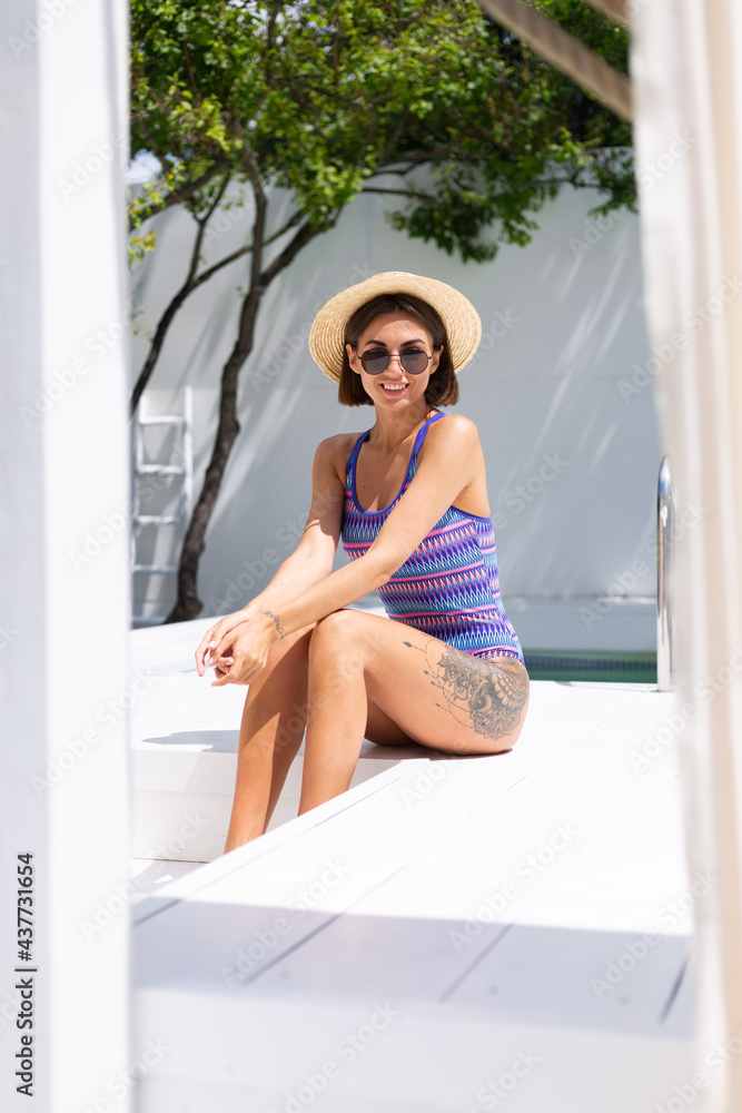 Beautiful woman in swimsuit at backyard pool at summer sunny day enjoying amazing warm weather, catching sun rays Beautiful woman in swimsuit at backyard pool at summer sunny day enjoying amazing warm weather, catching sun rays