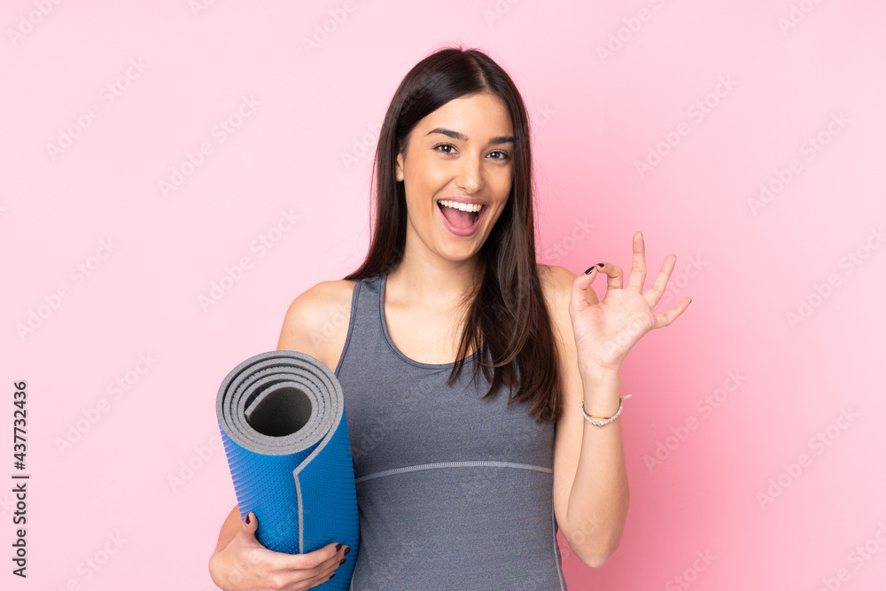 Young caucasian woman with mat isolated on pink background showing an ok sign with fingers Young caucasian woman with mat isolated on pink background showing an ok sign with fingers