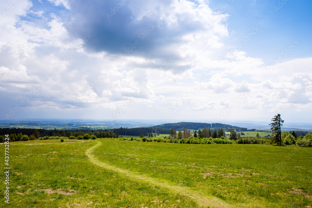 Landscape on Hoherodskopf, volcano region in Hesse, Germany. On cloudy sunny warm summer day, meadows, hills, fields and forests.
