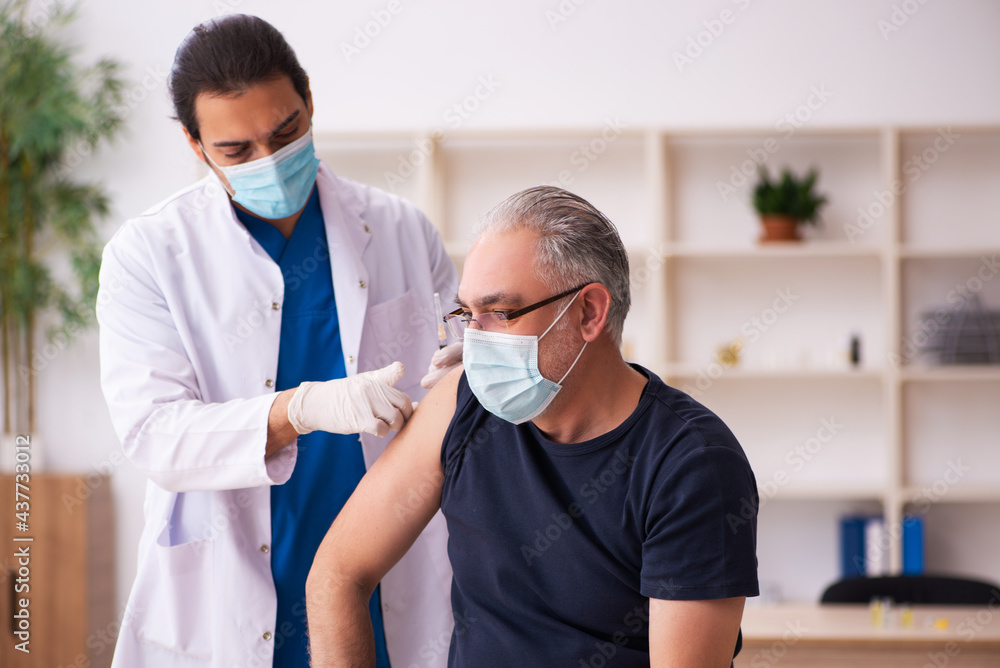 Old man visiting young doctor in covid-19 vaccination concept