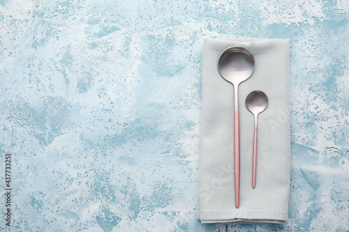 Clean spoons with napkin on color background © Pixel-Shot