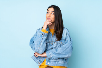 Young caucasian woman isolated on blue background thinking an idea while looking up