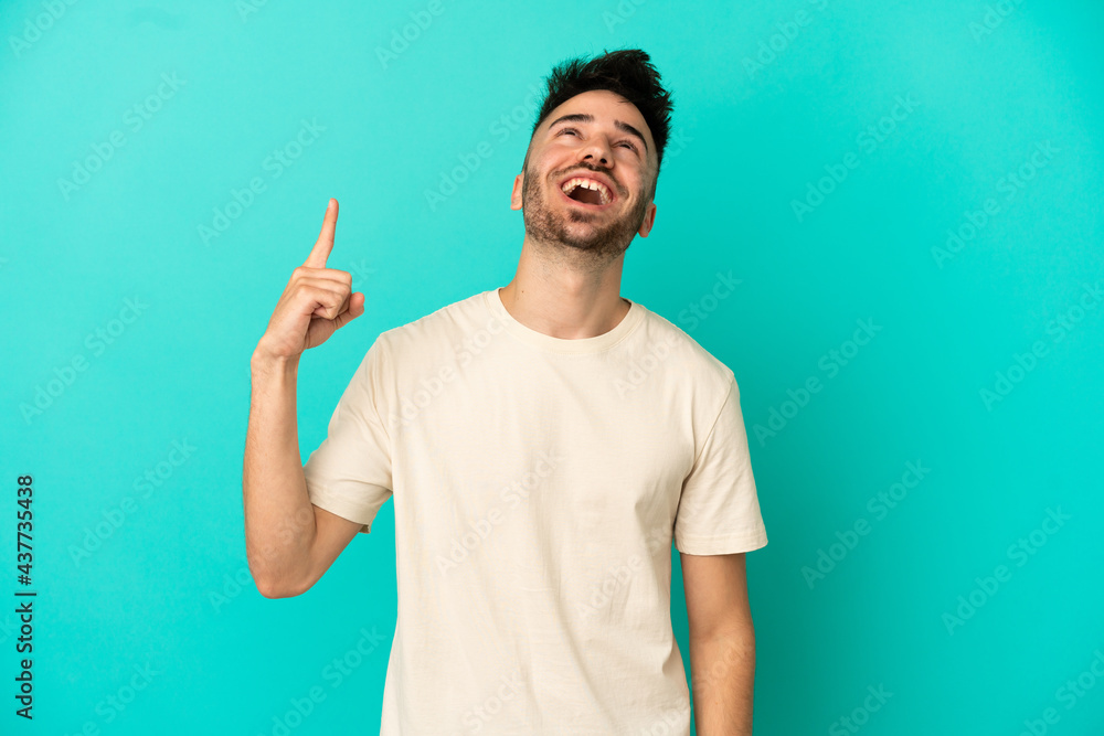 Young caucasian man isolated on blue background pointing up and surprised Young caucasian man isolated on blue background pointing up and surprised