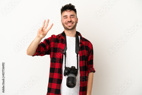 Young photographer caucasian man isolated on white background happy and counting three with fingers © luismolinero