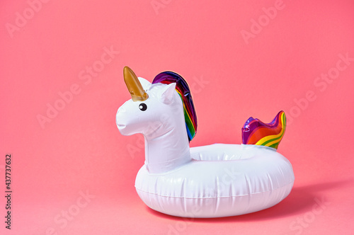 Inflatable white unicorn pool toy on pink background. Creative minimal concept