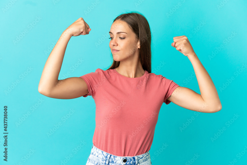 Young woman over isolated blue background doing strong gesture Young woman over isolated blue background doing strong gesture
