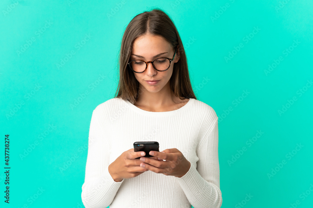 Young woman over isolated blue background using mobile phone Young woman over isolated blue background using mobile phone