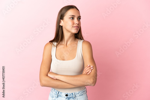 Young woman over isolated pink background looking to the side