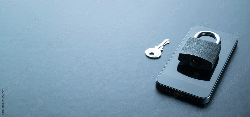 Fototapeta premium Internet protection. Modern space grey mobile phone with padlock, key on dark background. Darkweb, darknet and hacking concept.