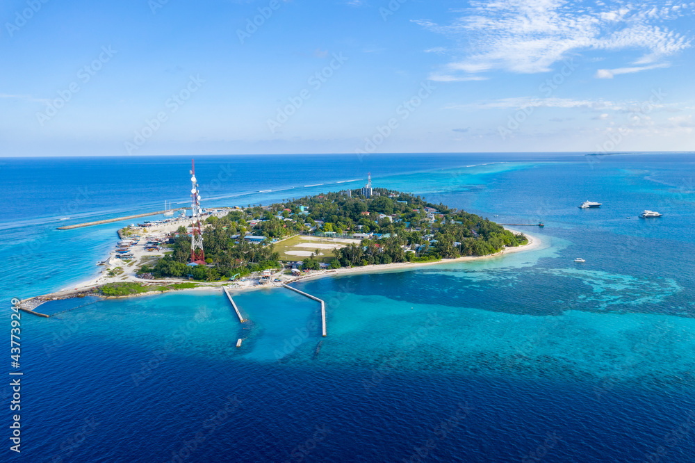 Aerial view of the Maldives island in the Indian ocean with a fishing village, marina for small ships and a cell tower