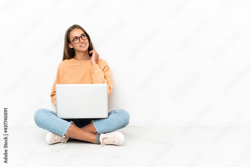 Young woman with a laptop sitting on the floor thinking an idea Young woman with a laptop sitting on the floor thinking an idea