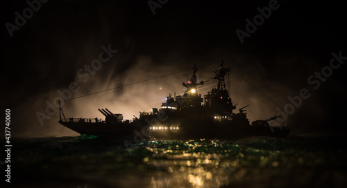 Silhouettes of a crowd standing at blurred military war ship on foggy background. Selective focus. © zef art