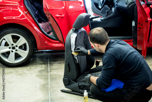 Car service worker cleans a car seat with a special brush