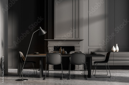 Minimalistic grey dining room interior with long table, black chairs and fireplace