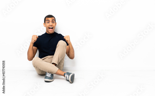 African American man sitting on the floor celebrating a victory in winner position