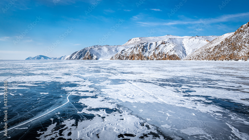 The transparent ice of Lake Baikal is dusted with snow