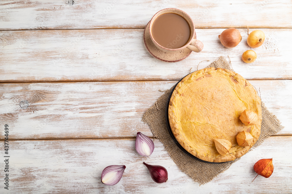 Autumn onion pie and cup of coffee on white wooden background. Top view, copy space.