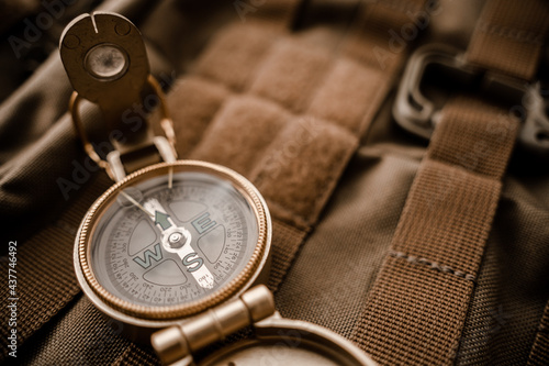 golden compass on tactical or travel backpack, shallow DOF, focus on dial. Concept for direction, travel, guidance or assistance.