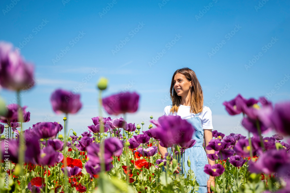 Happy brunette woman in white shirt and blue skirt standing in field of wild purple flowers. Smile is on her face. Happiness. Enjoy life. Relax. No stress. Village life. Sunny day. Happy brunette woman in white shirt and blue skirt standing in field of wild purple flowers. Smile is on her face. Happiness. Enjoy life. Relax. No stress. Village life. Sunny day.
