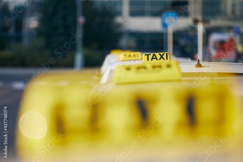 Selective focus on taxi sign on roof. Car waiting for passenger in city street.