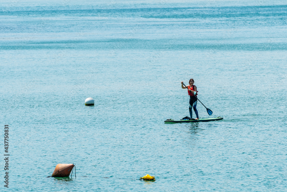 Naklejka premium A young woman paddle surfing in the sea in Urdaibai, a Bizkaia biosphere reserve next to Mundaka. Basque Country