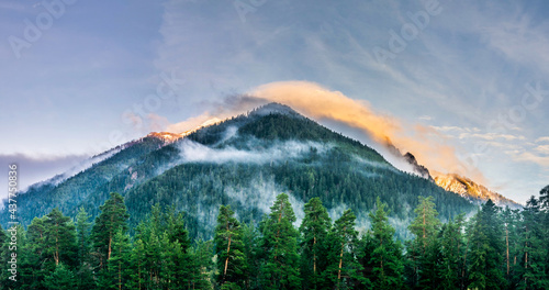 Panoramic landscape view, snow covered mountain peaks and colorful clouds over mountain range during sunset, Arkhyz villadge, Caucasus mountains, Russia