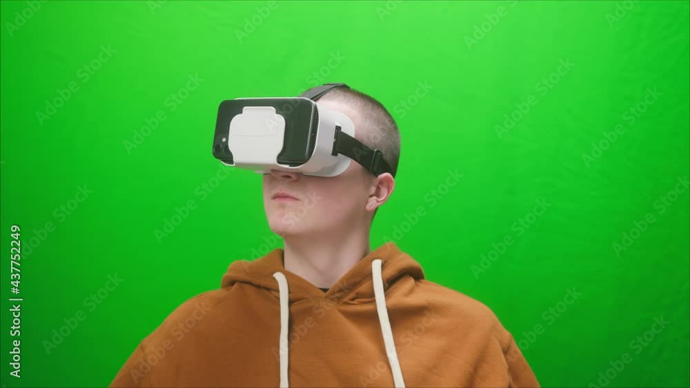 Close-up of young man wearing virtual reality glasses, playing vr video games. Student enjoying AR 3D video games on green background, modern console, next gen 2020, new era of consoles. Close-up of young man wearing virtual reality glasses, playing vr video games. Student enjoying AR 3D video games on green background, modern console, next gen 2020, new era of consoles.
