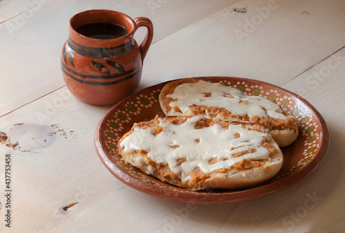 Molletes on a mexican mud plate and black coffee in a mexican mud cup on a wooden table, as part of Mexico traditional breakfast. photo