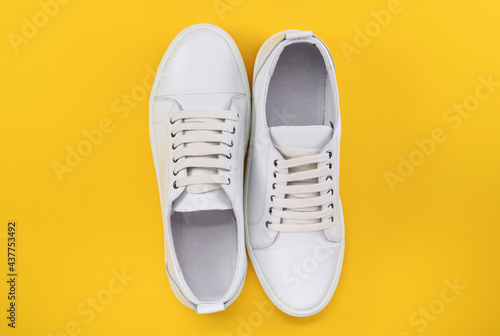 Fashionable white sneakers, sneakers on a colored yellow background, minimalism, top view, creative layout.
